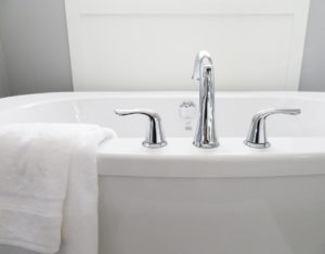 Close up shot of a white porcelain bathtub with a towel hanging over the side.